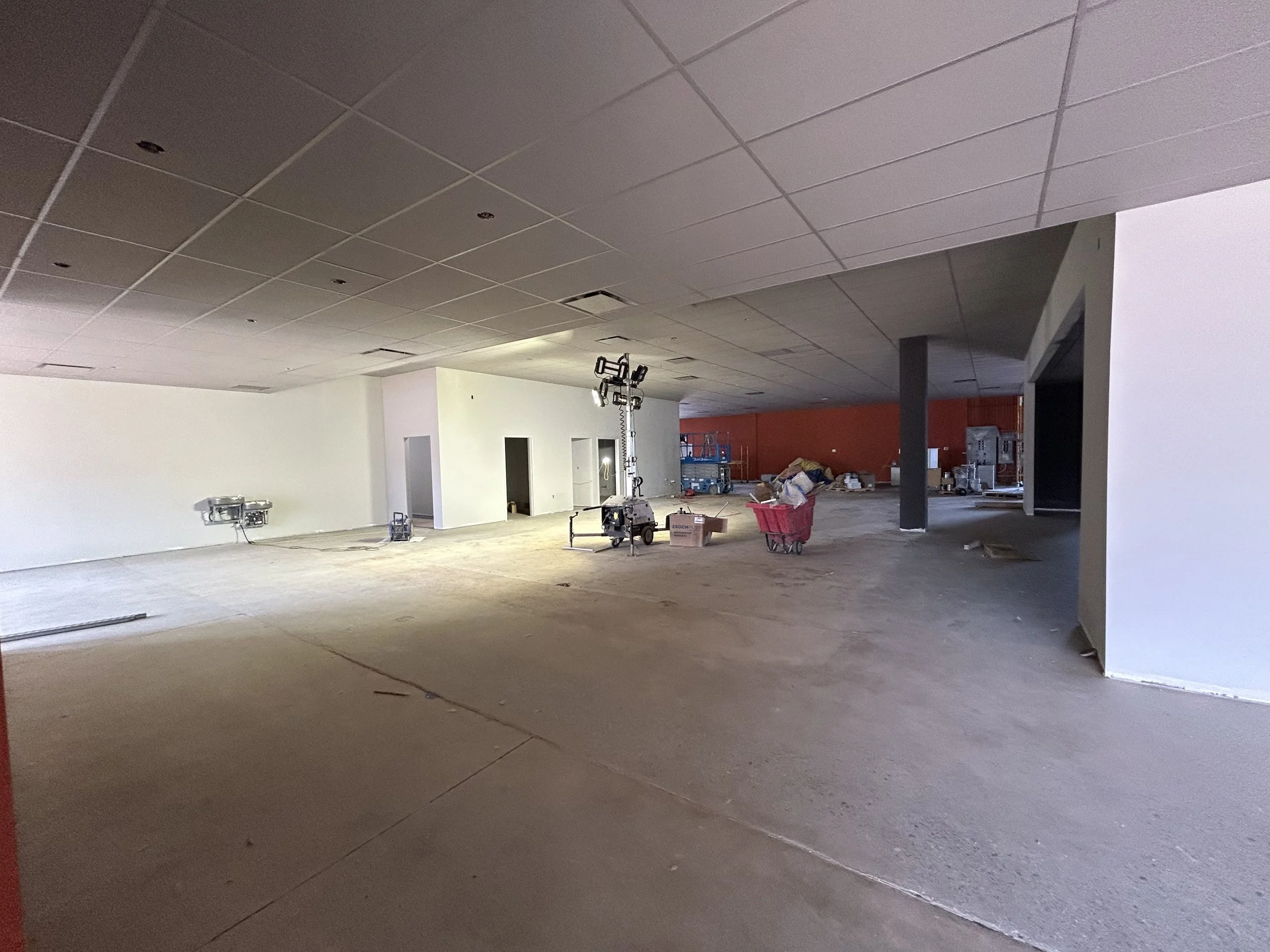 Crucible Fit buildout progress with an open interior, unfinished ceiling, and construction materials.