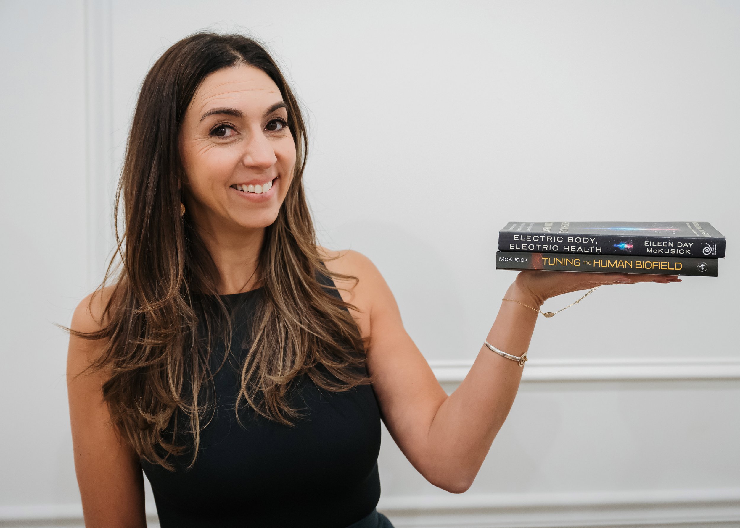 Amanda Gandolfo holding books on Biofield Tuning and the human biofield
