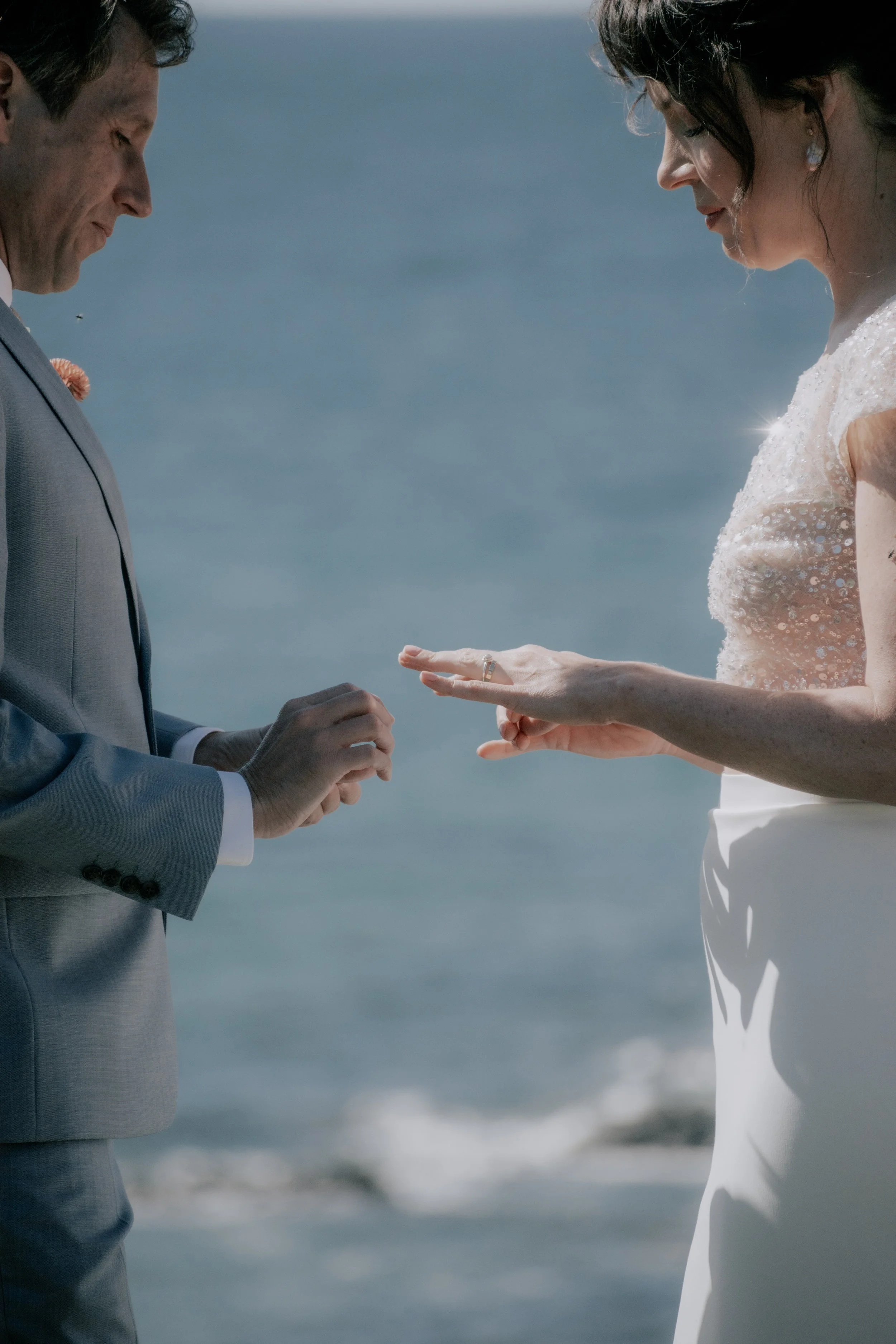 A bride and groom exchanging rings during a wedding ceremony at the beach.