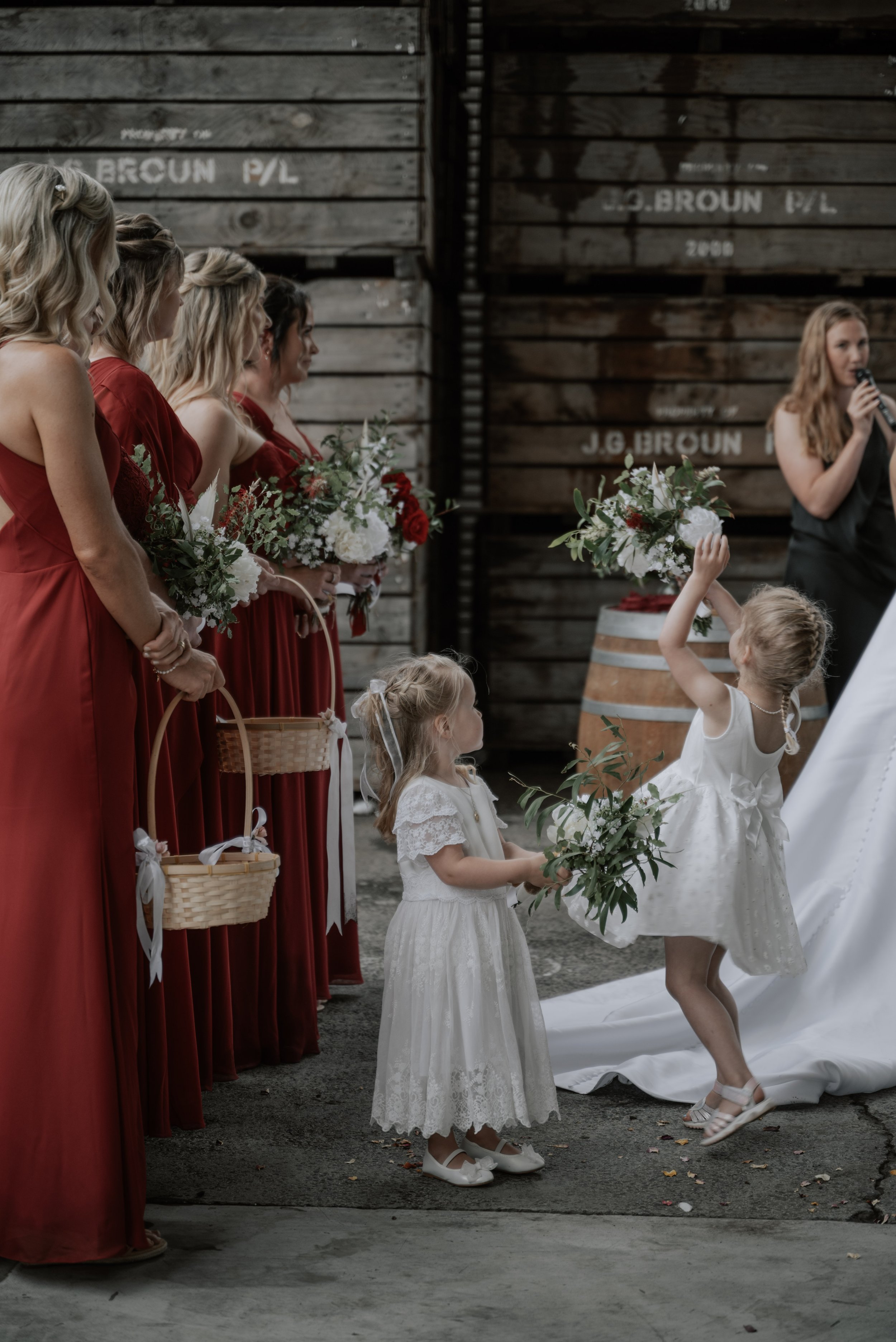 Two flower girls twirl and dance with floral bouquets in front of bridesmaids during a wedding ceremony