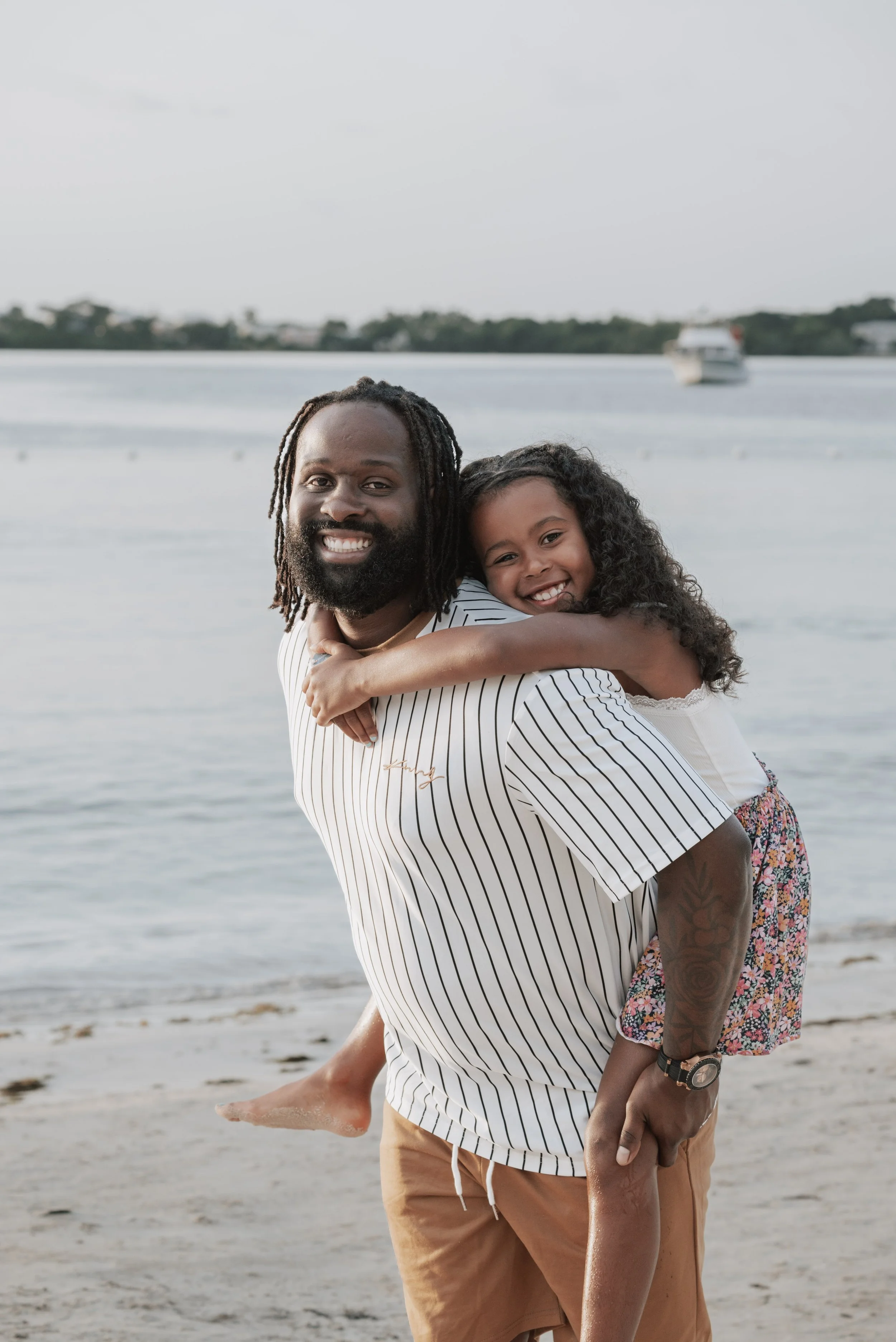 Black father and daughter hugging on a beach at sunset
