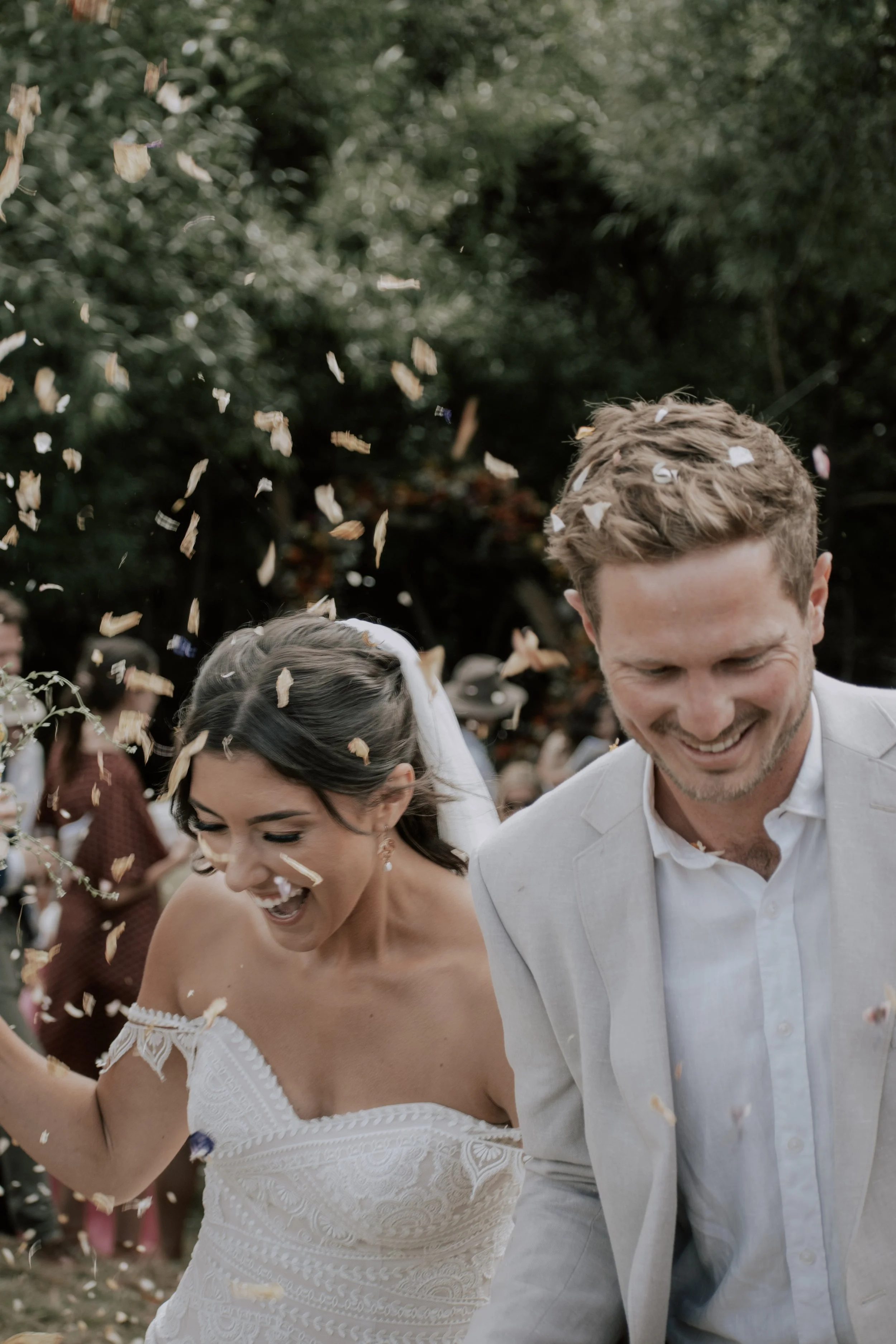 A just married couple laugh as confetti is thrown at them