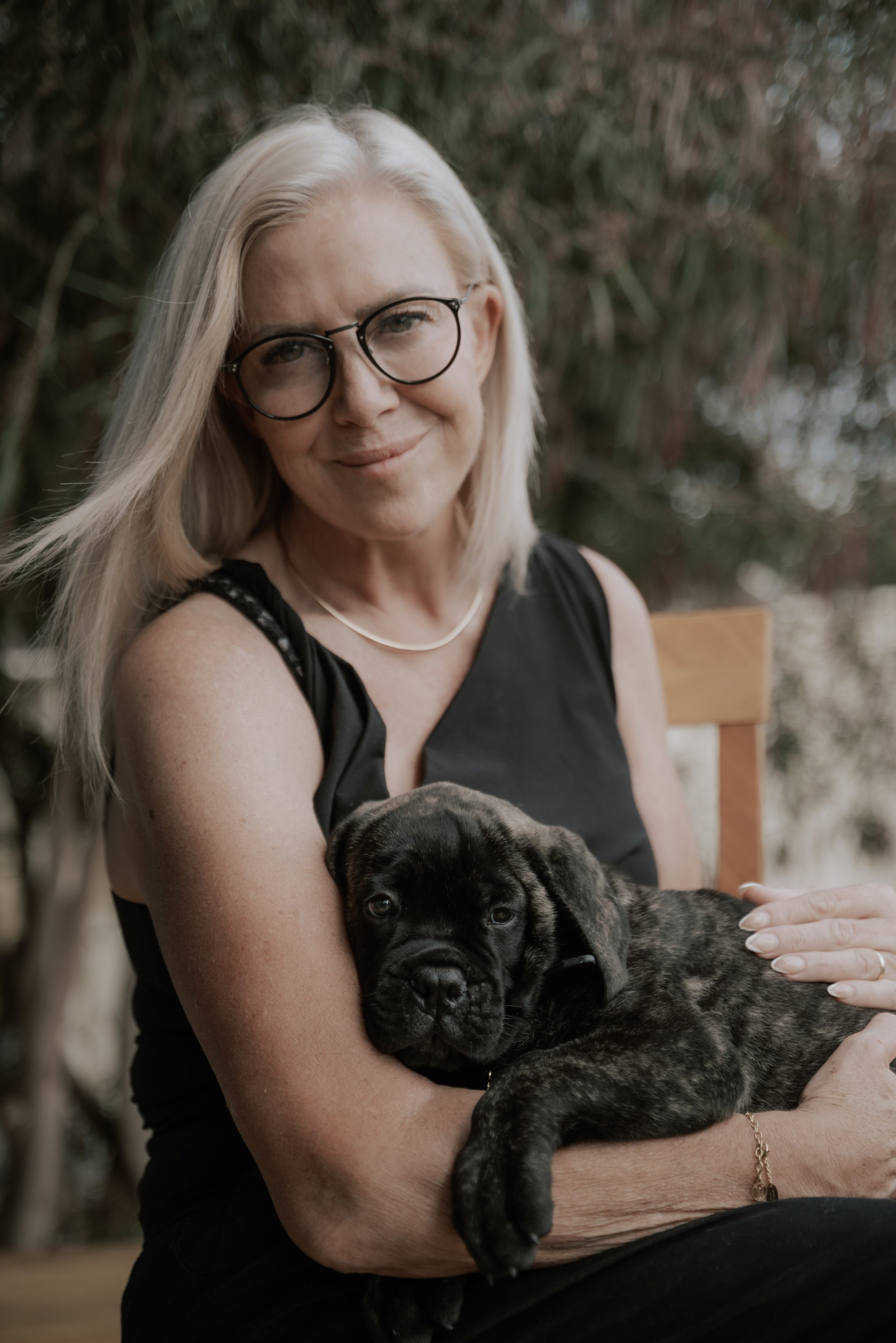 A blonde woman holding her new puppy while smiling at the camera