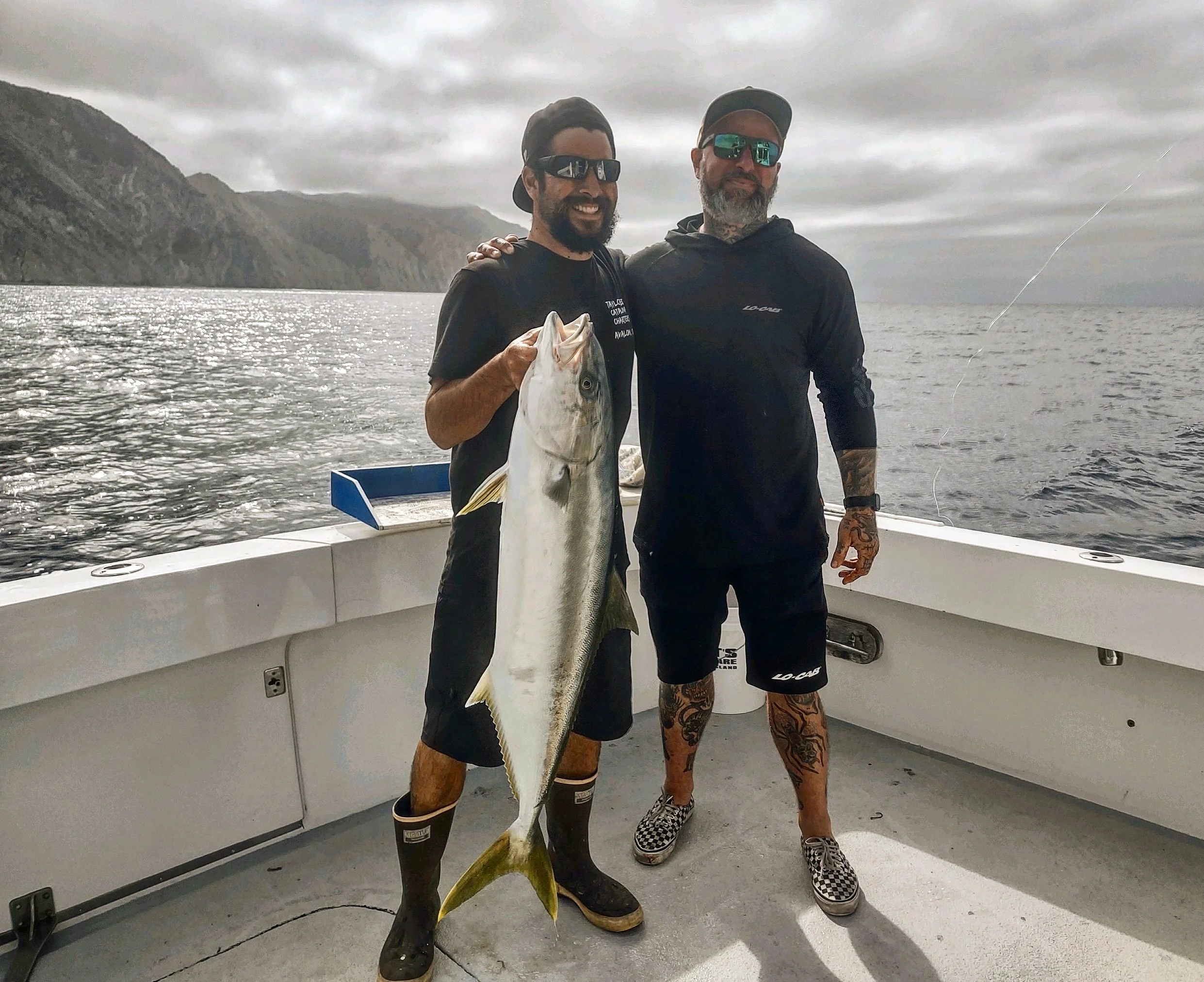 Two men holding a large fish aboard Taylored Catalina Charters fishing charter yacht Breann's Revenge on Catalina Island