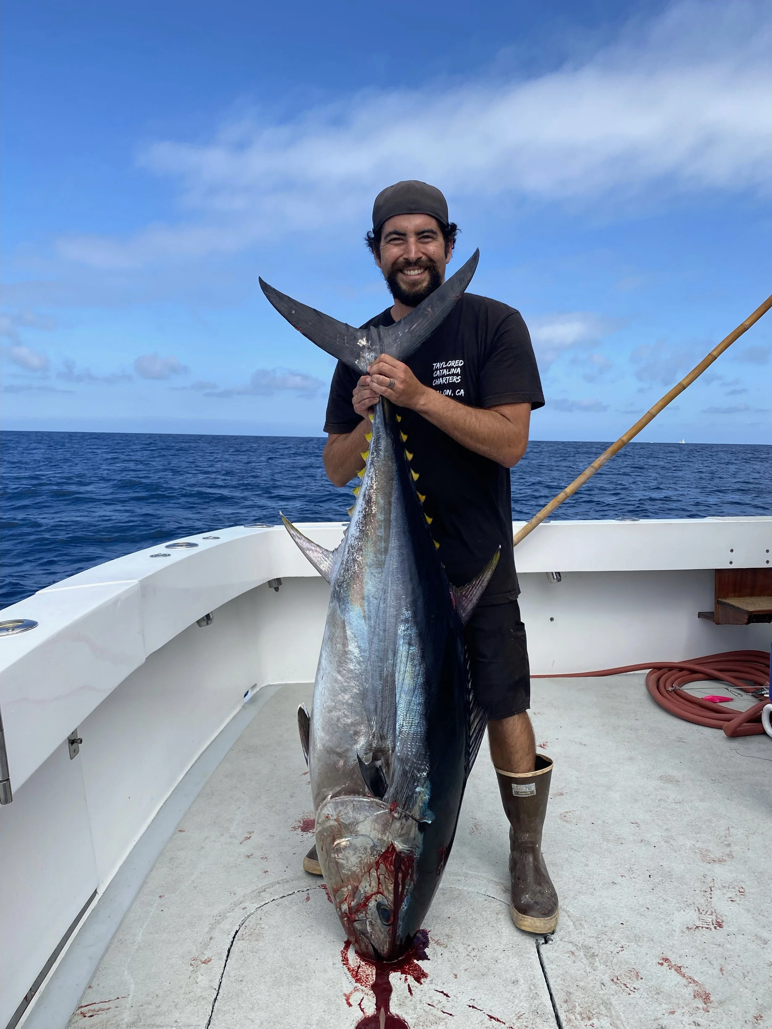 Captain holding a large bluefin tuna aboard Taylored Catalina Charters fishing charter yacht Breann's Revenge on Catalina Island