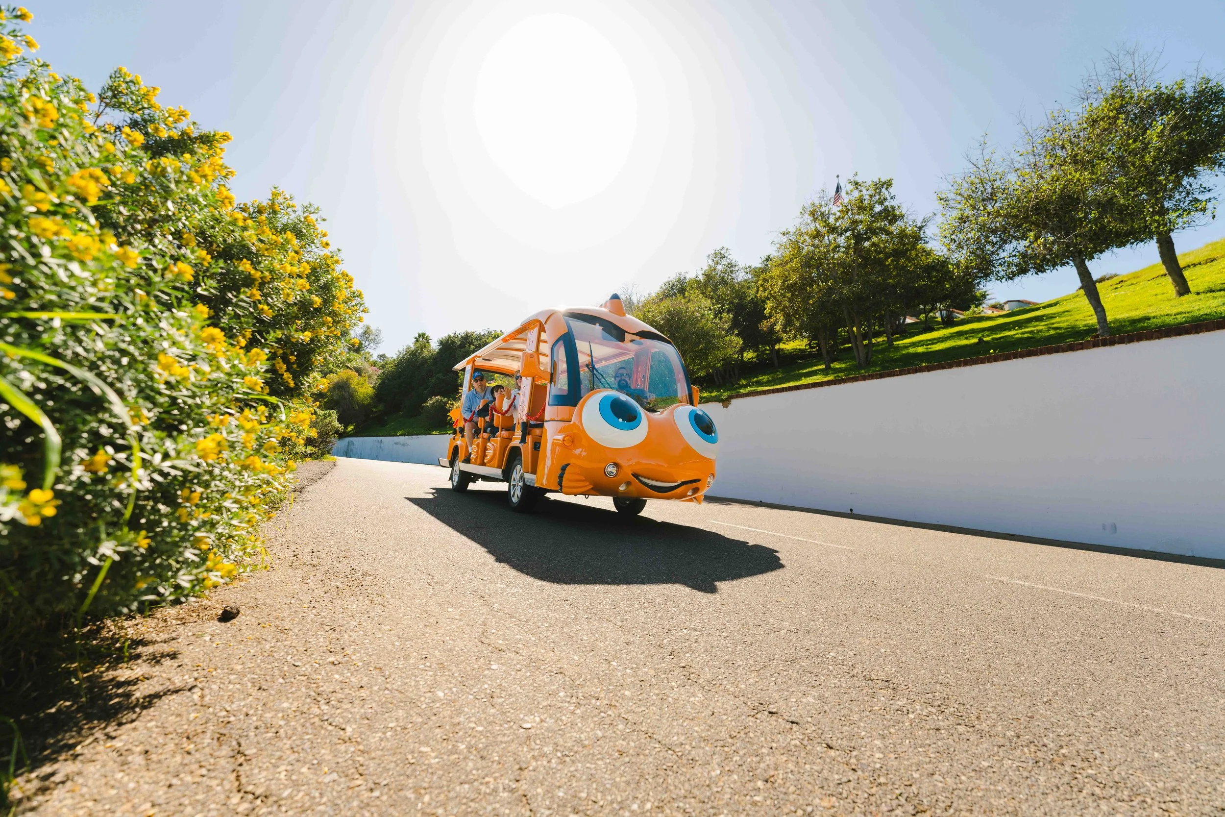 Group of a smiling large family, including adults and children, in front of the scenic coastal background of the Avalon Harbor on Catalina Island, next to Gary the Garibaldi.