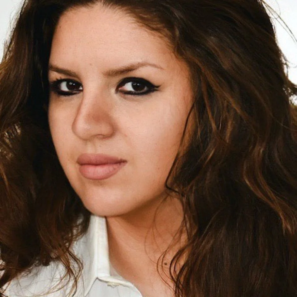 Ragazza con lunghi capelli castani e trucco marcato, guardando l'obiettivo