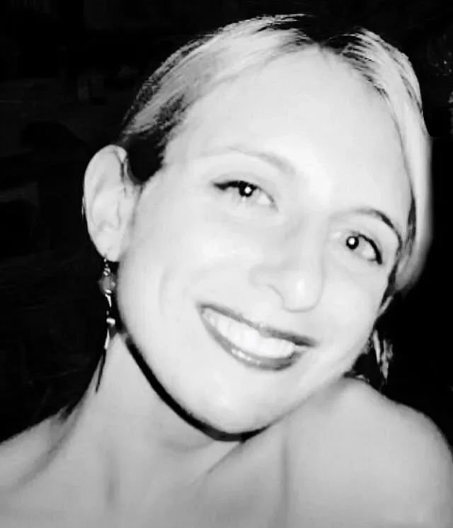 A black and white photo of a smiling woman with short hair and earrings.