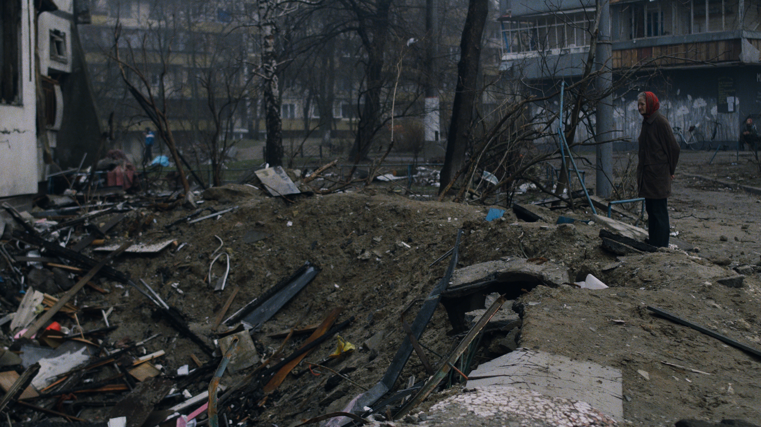Photo of a bomb crater beside a building in an urban neighborhood
