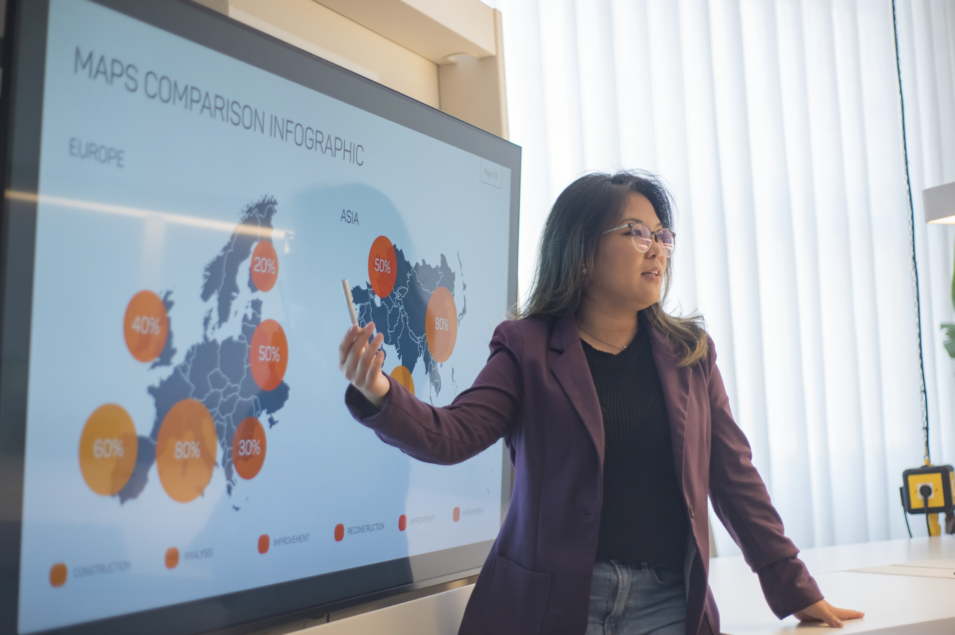 Woman in business attire gestures toward a large digital monitor featuring a map-based infographic