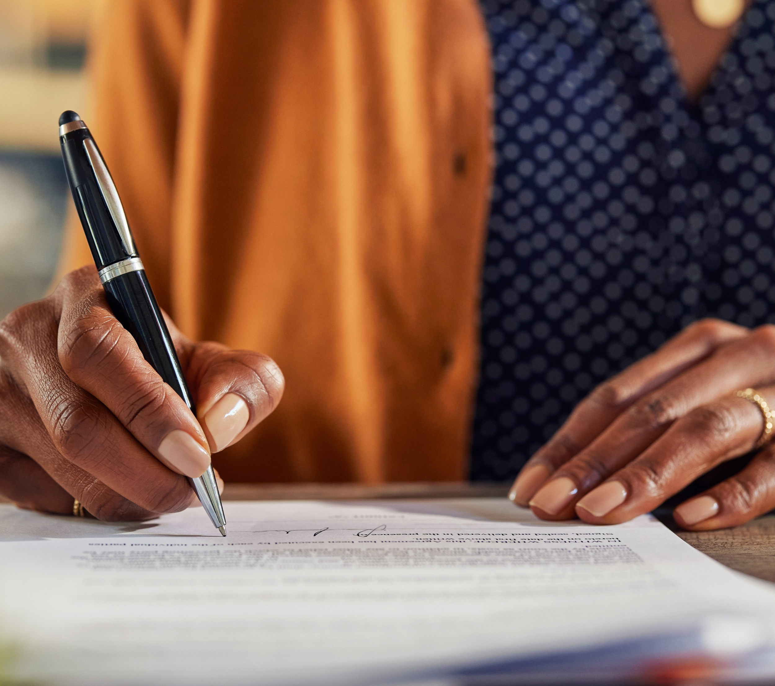 Closeup photo image of a person's hand signing with a ball point pen