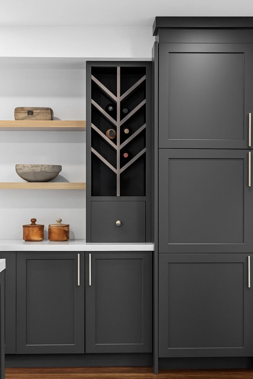 Modern kitchen with dark gray cabinets, open shelving, and a wine rack built into the cabinetry. Wooden bowls and containers are placed on the shelves and counter.