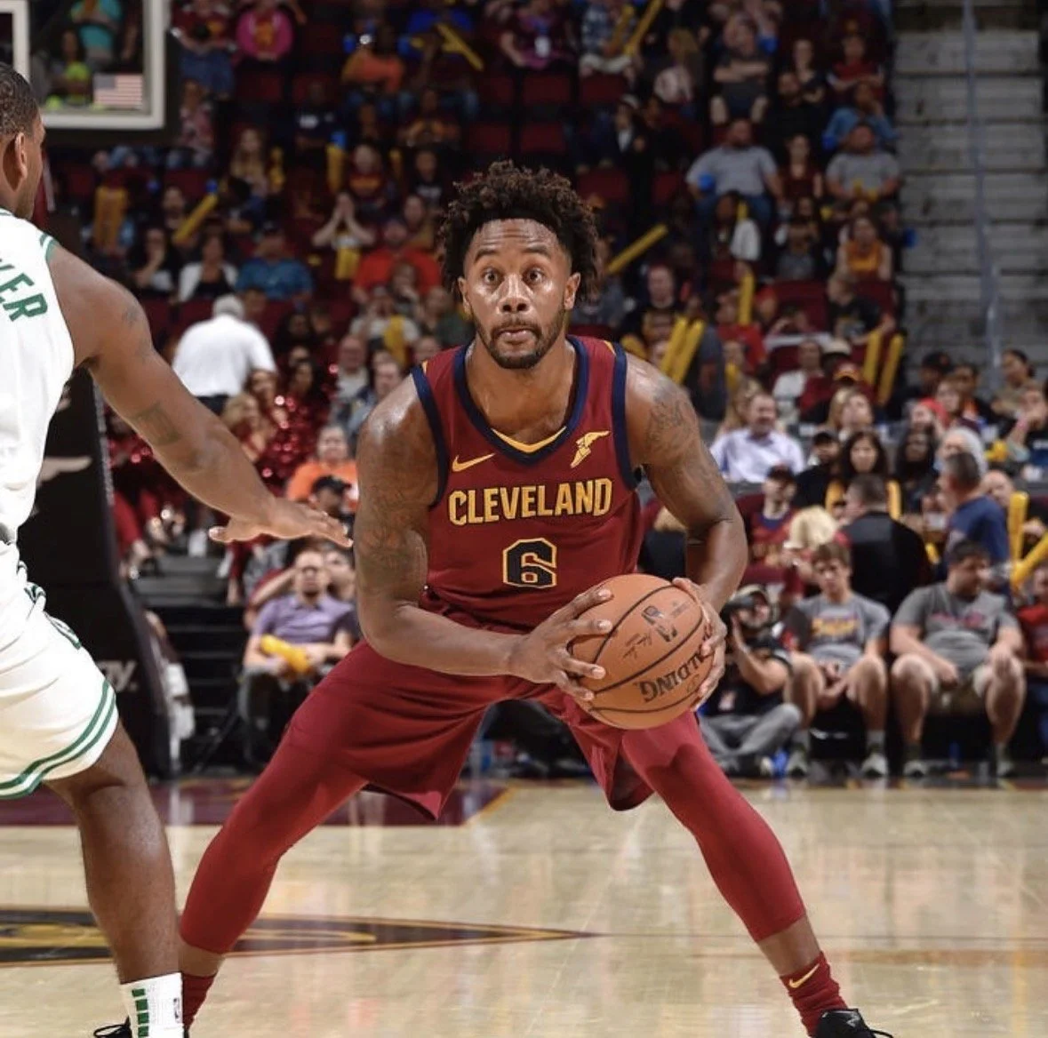 A basketball player from Cleveland wearing a maroon and yellow jersey with the number 6, holding a basketball on the court during a game.