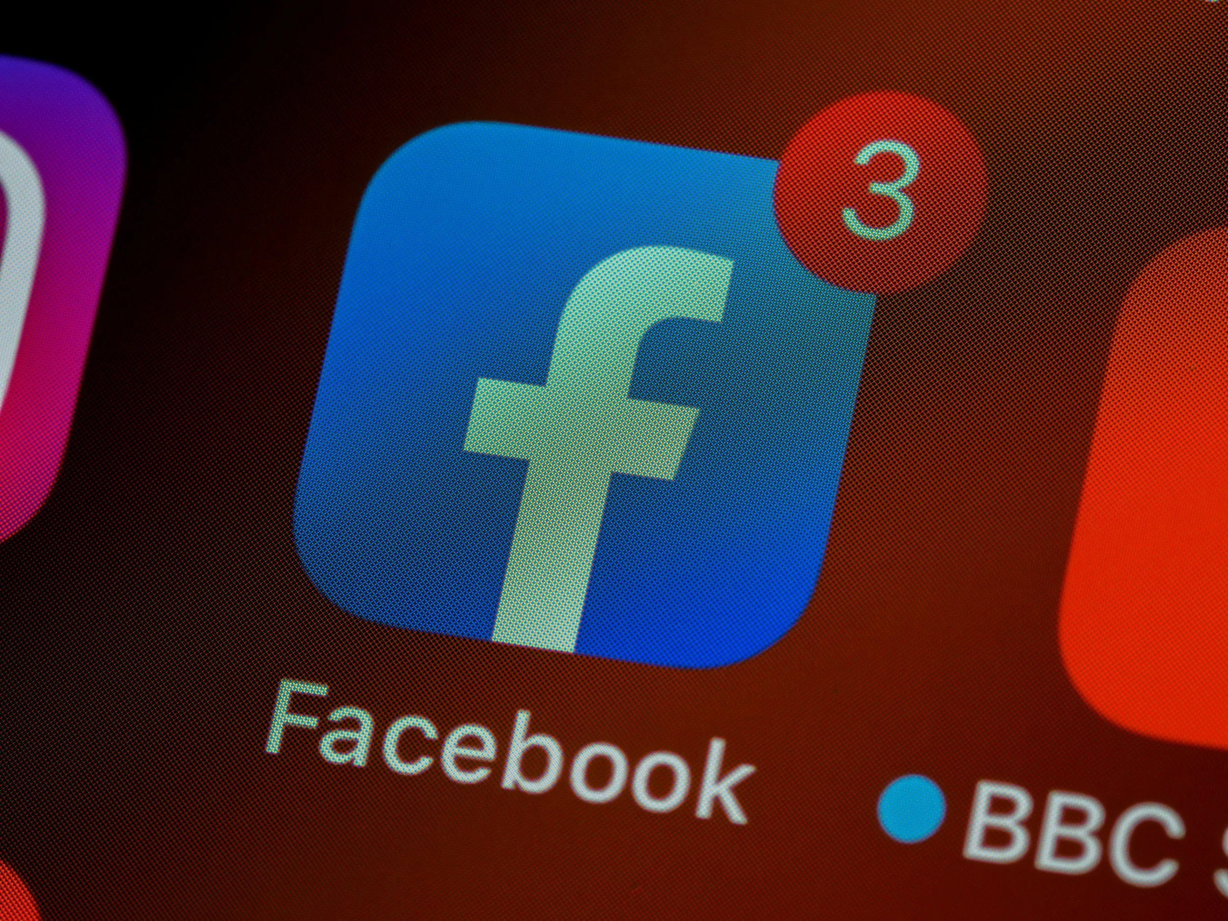 Close-up of a mobile device screen showing the Facebook app icon with a notification badge indicating three new notifications.