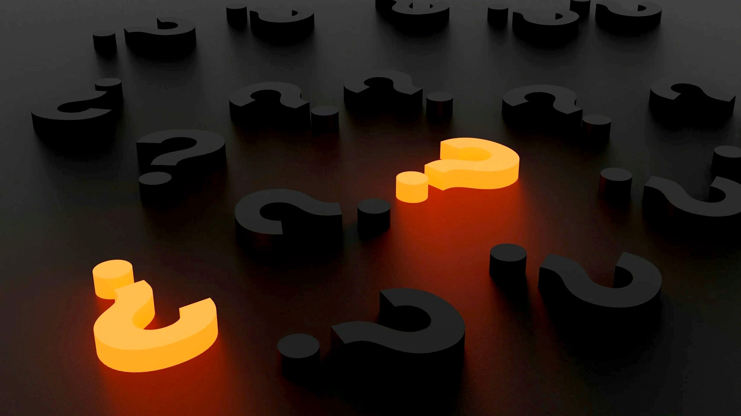 Several black question marks on a dark surface with two orange illuminated question marks among them.