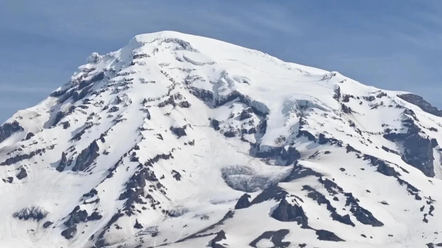 Snow-covered mountain with rocky outcrops and a glacier in the middle.