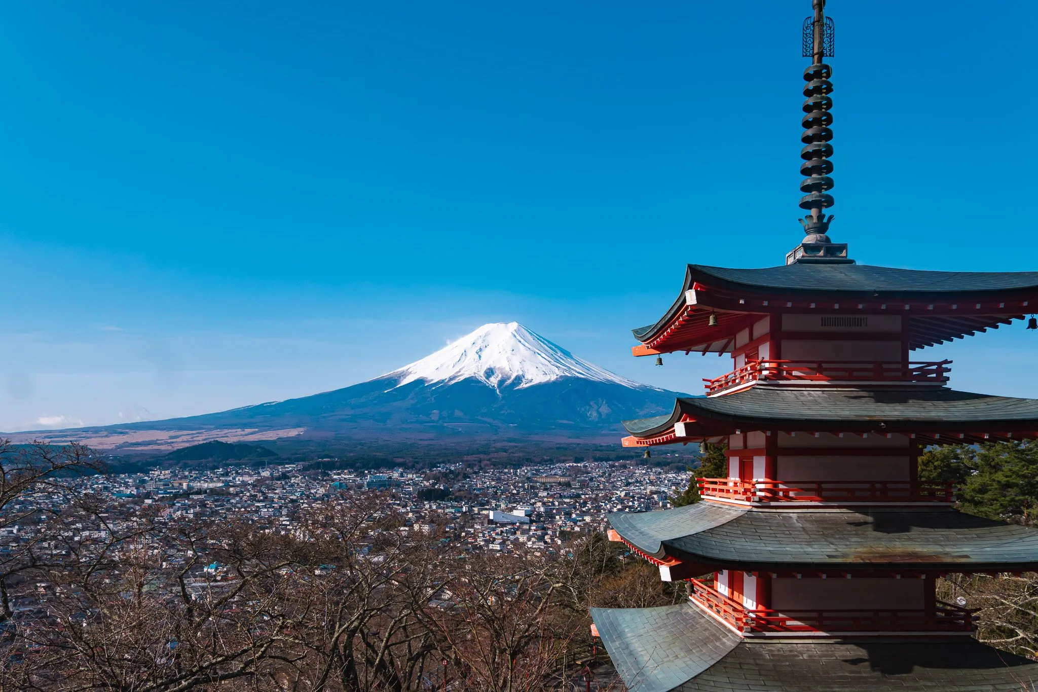 Chureito Pagoda, a five-story red pagoda in Arakura Sengen Park, Fujiyoshida, Japan, with Mount Fuji snow-capped and clear blue sky in the background.