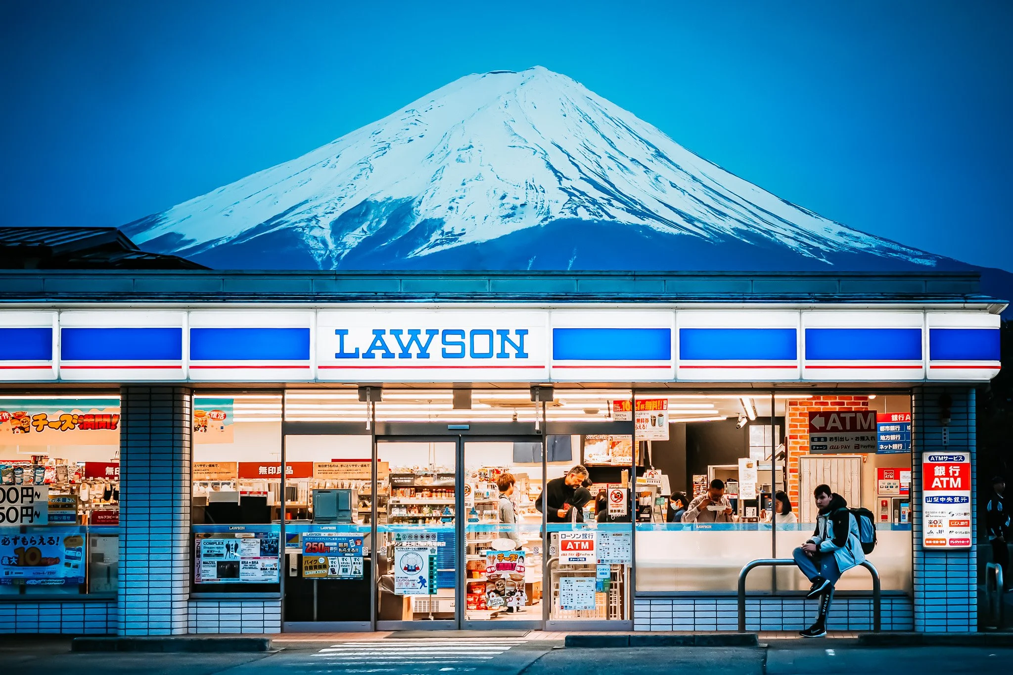 A Lawson convenience store in Japan with Mount Fuji in the background, taken at dusk.