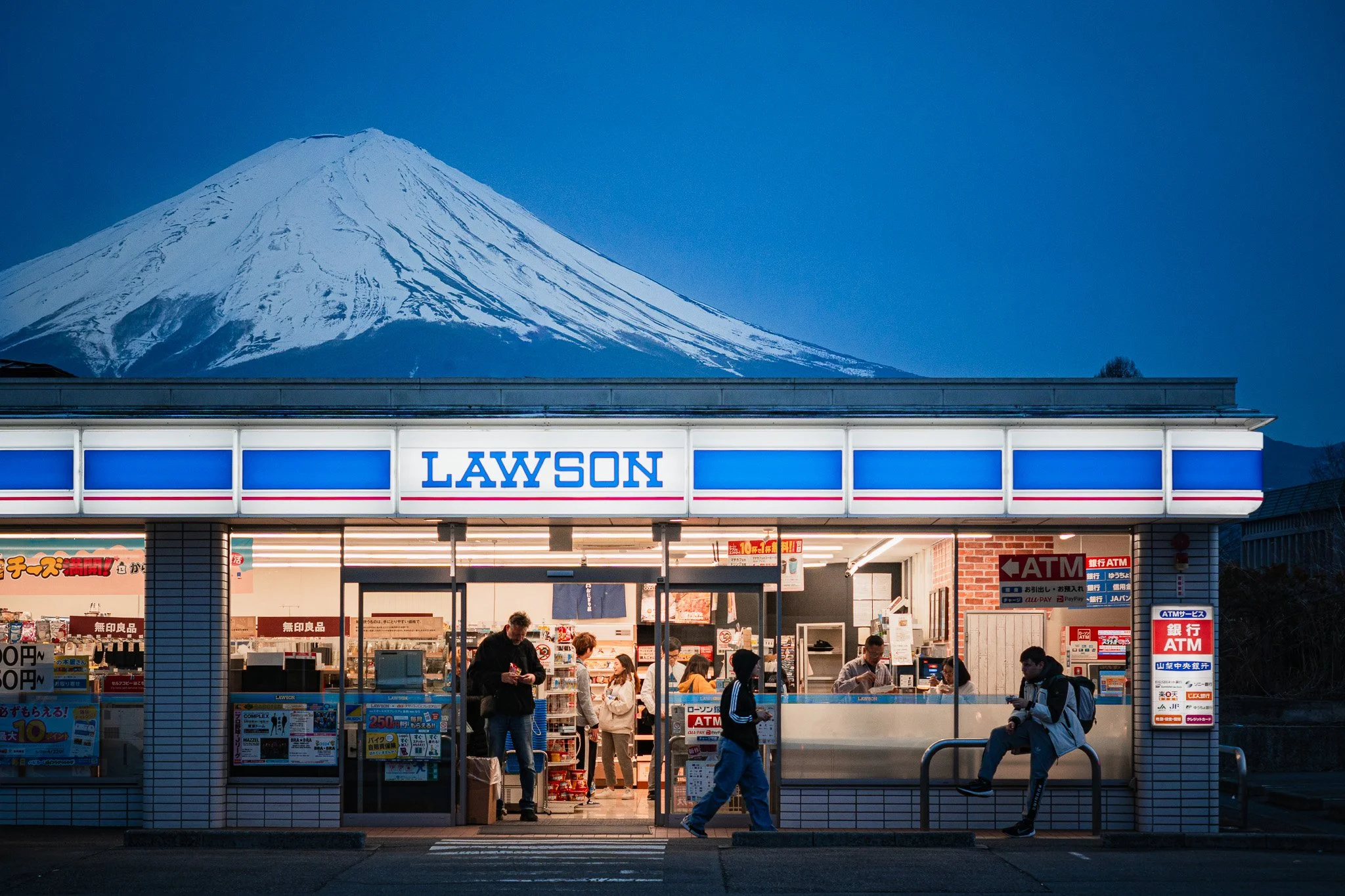 A Lawson convenience store with Mount Fuji in the background during dusk.