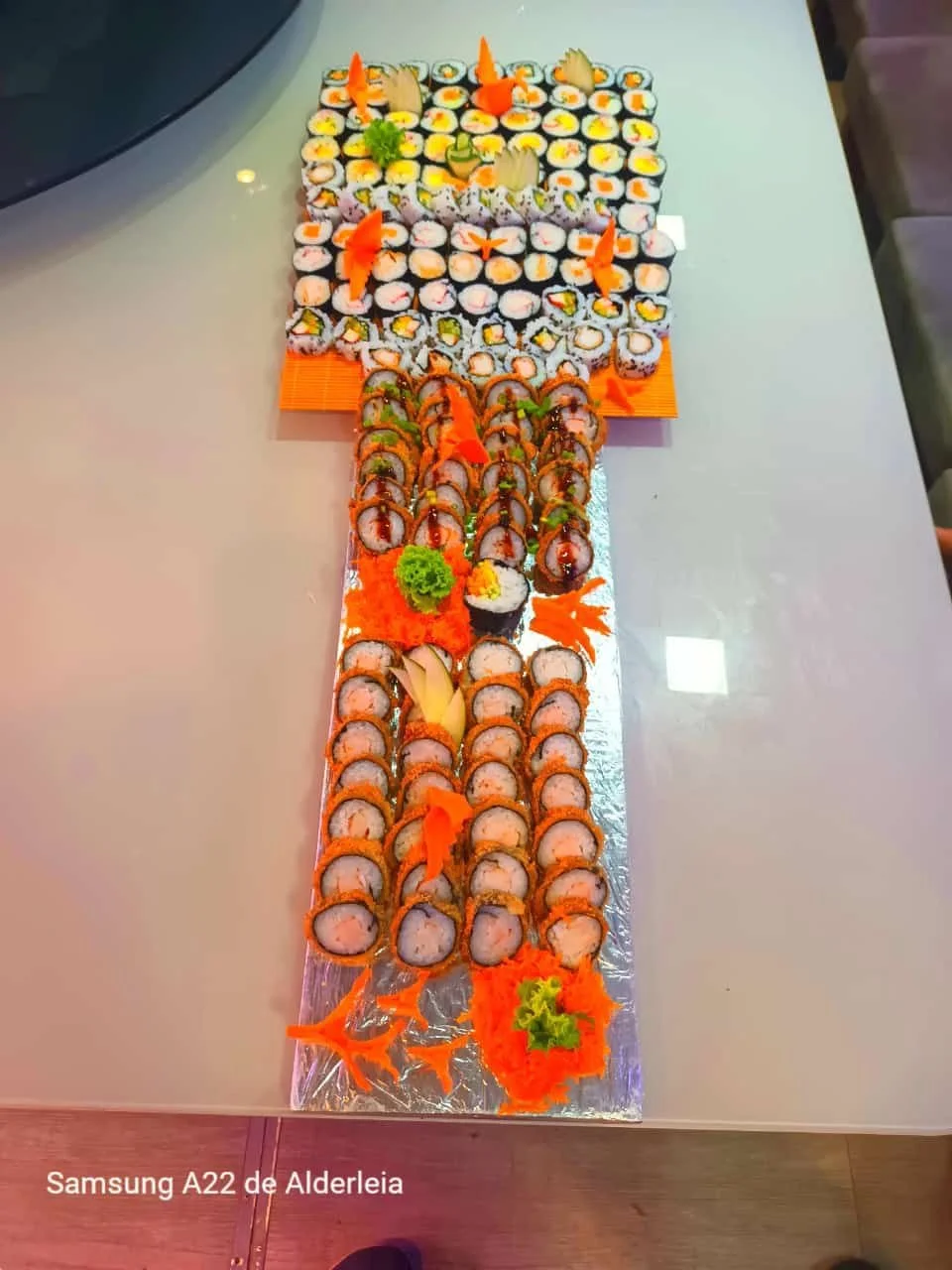 Display of assorted sushi rolls arranged on a rectangular tray decorated with garnishes, including shredded carrots, lettuce, and wasabi.