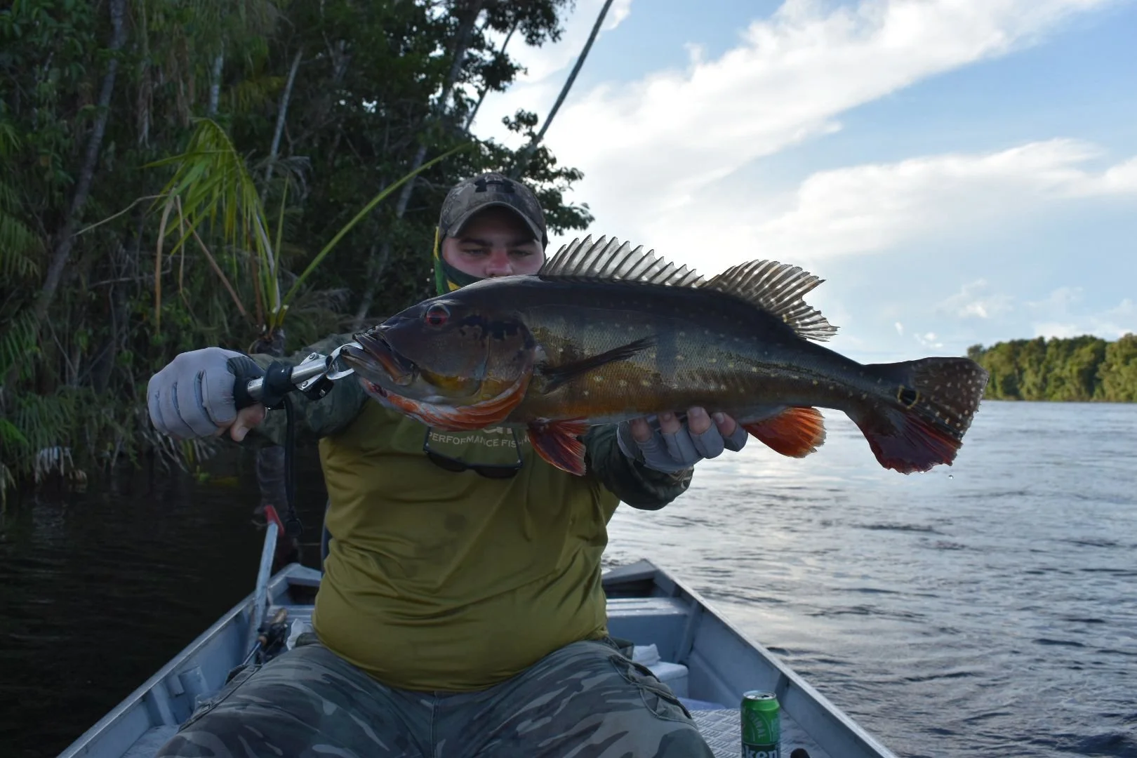 A man on a boat holding a large fish he caught.
