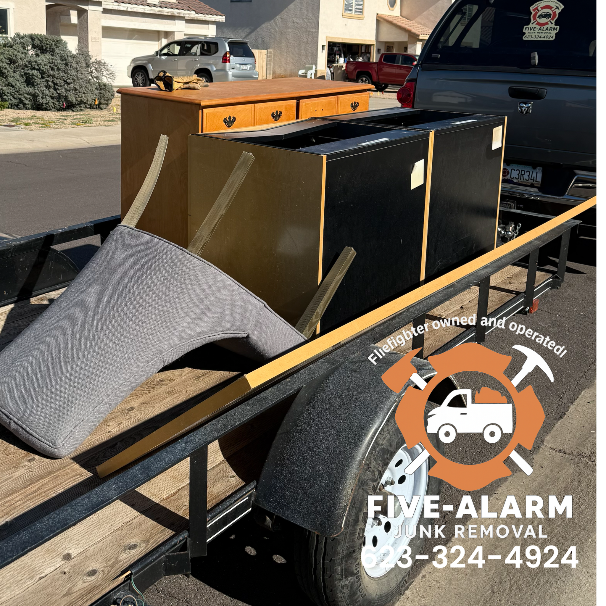 A trailer loaded with furniture and household items parked on a street, with a logo overlay for Five-Alarm Junk Removal.