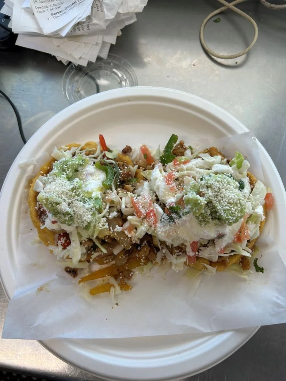 Sopes topped with cabbage, tomatoes, onions, cilantro, cheese, and sour cream