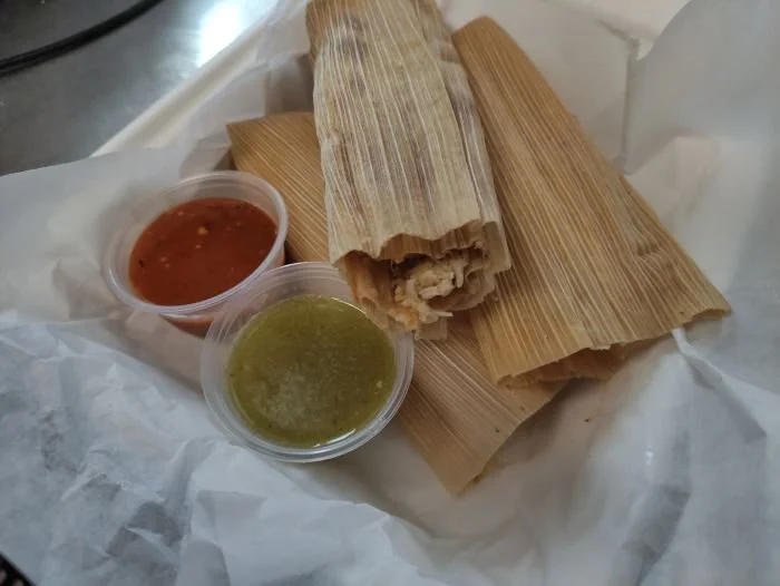 Tamales with two sauce cups, one red and one green,