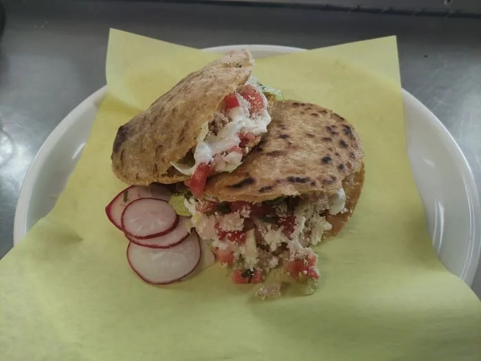 Gorditas with chopped tomatoes, lettuce, sour cream, and radish slices