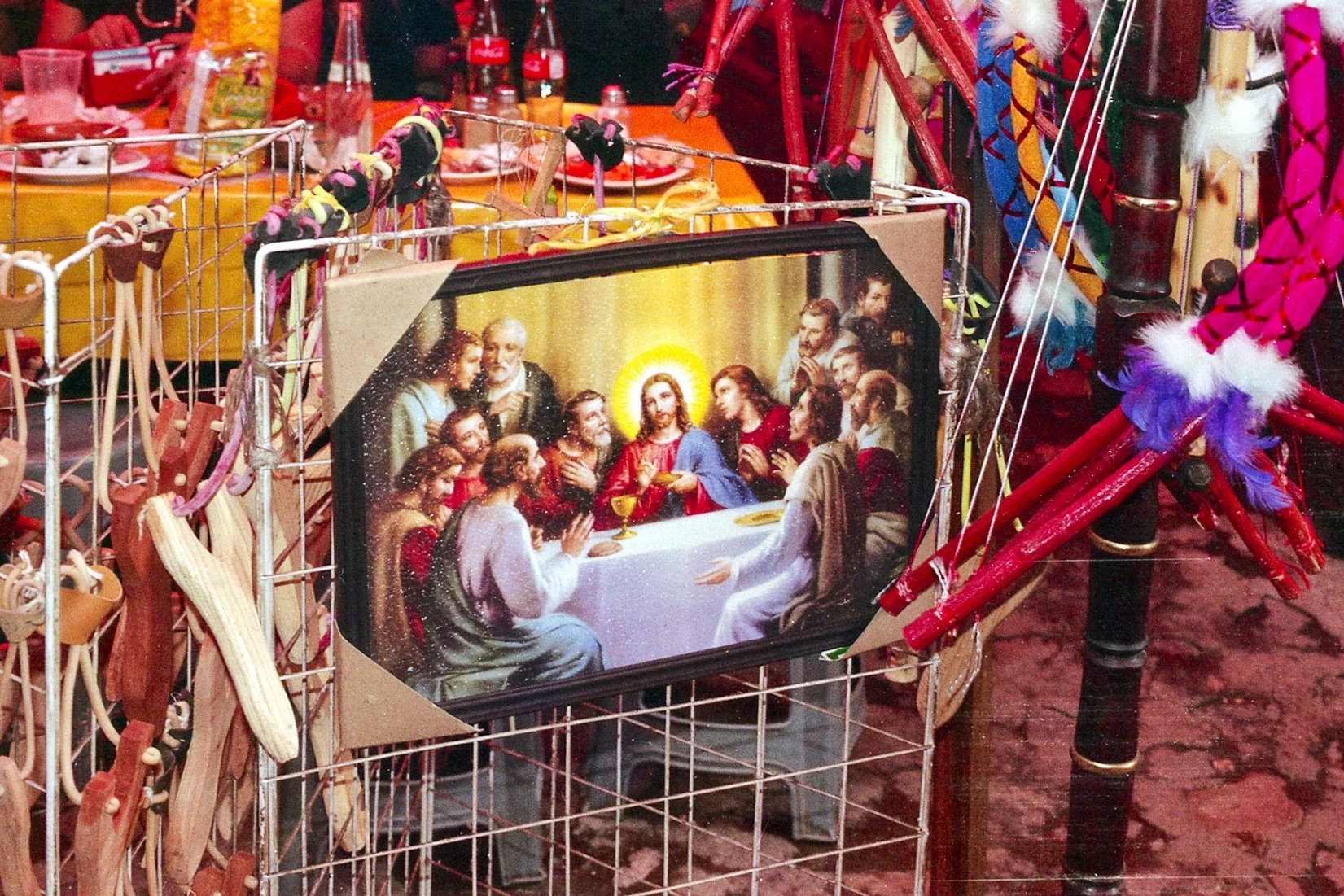 Una cartulina con una imagen de la Última Cena rodeada de accesorios navideños, en una tienda o mercado