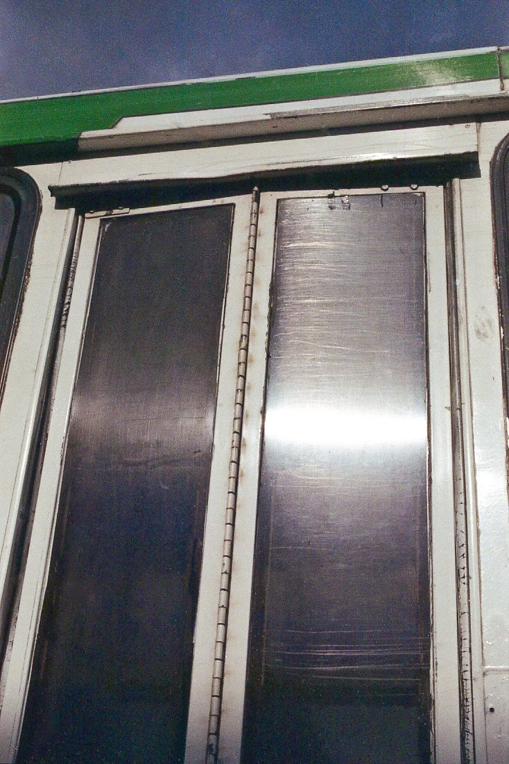 Puerta metálica enrollable o reja, con marco de color blanco y detalles en negro, en el ingreso de una estructura de construcción industrial o comercial.