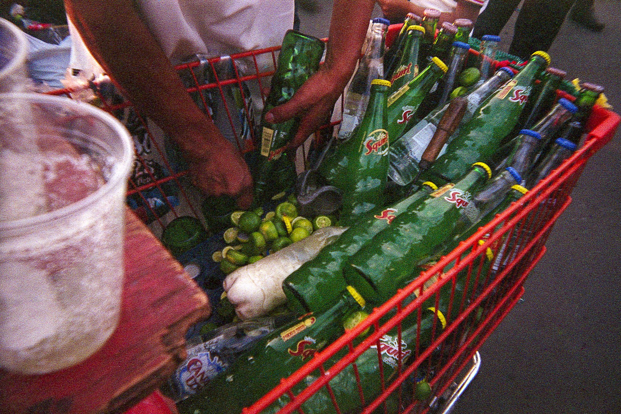 Persona comprando botellas de Sprite en un carrito de supermercado.
