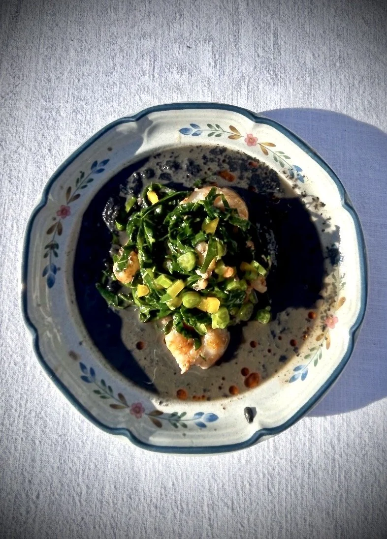 A bowl of seafood and vegetables in a creamy sauce on a white tablecloth.