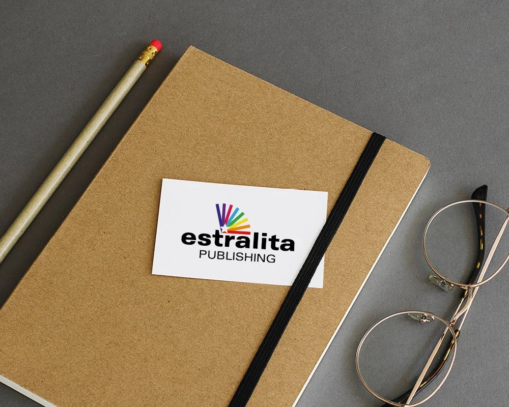 A brown notebook with a black elastic band, a white sticker with the publishing company logo, a pair of glasses, and a pencil with a pink eraser on a grey background.