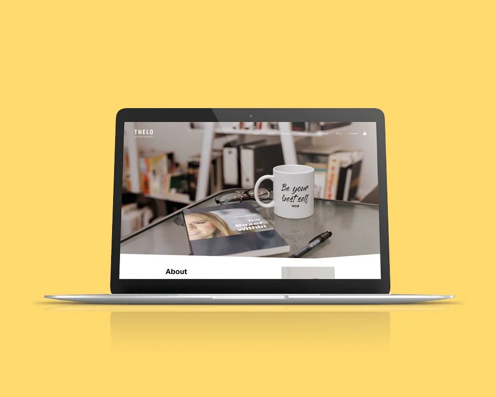 Laptop displaying a website with a background of a bookshelf, a coffee mug, a pair of glasses, a magazine or book, and a pen on a desk.