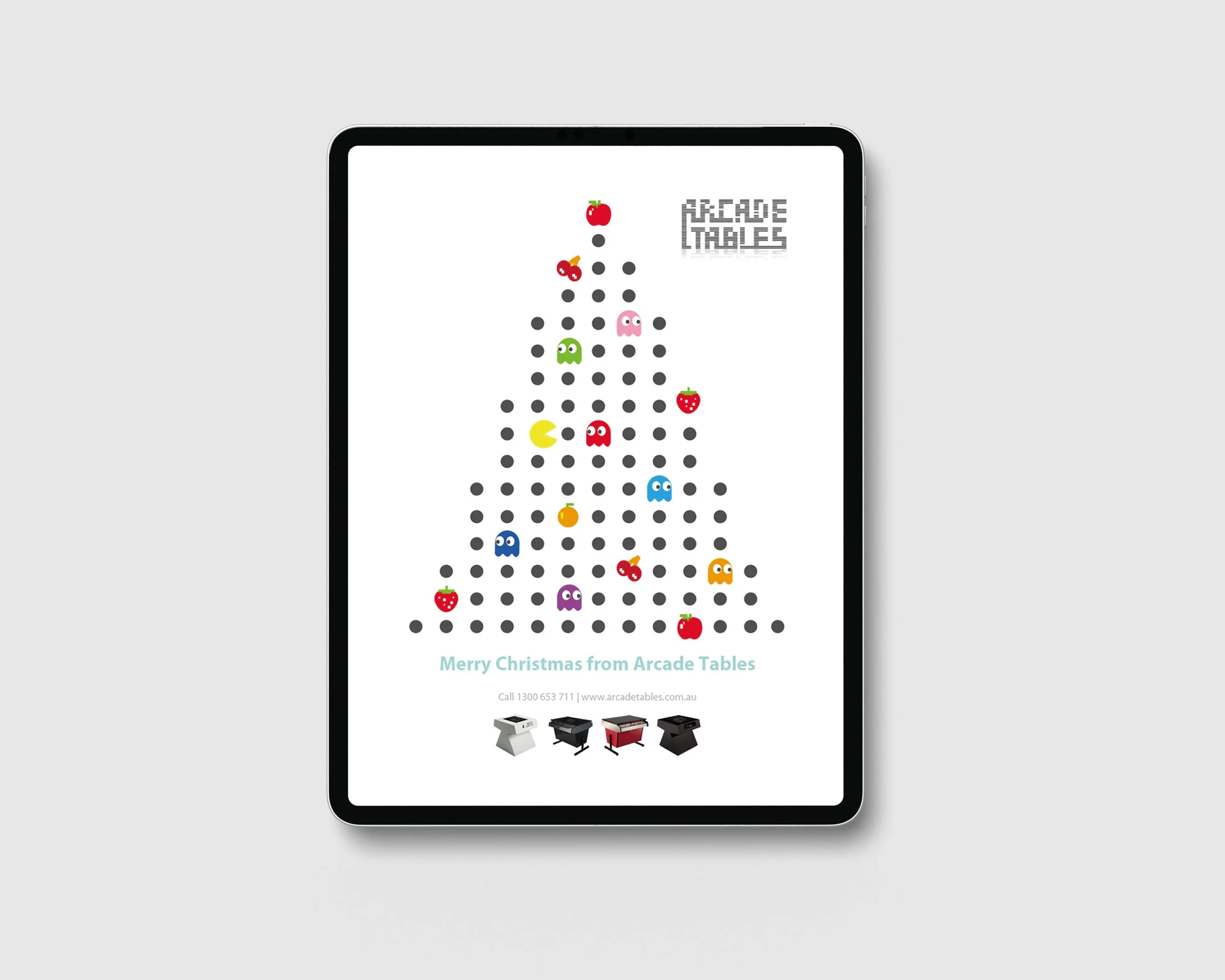 A digital illustration of a Christmas tree made of black dots with various colored Pac-Man style characters and fruit icons, including apples, strawberries, and bananas, arranged on the tree, with the message 'Merry Christmas from Arcade Tables' at t