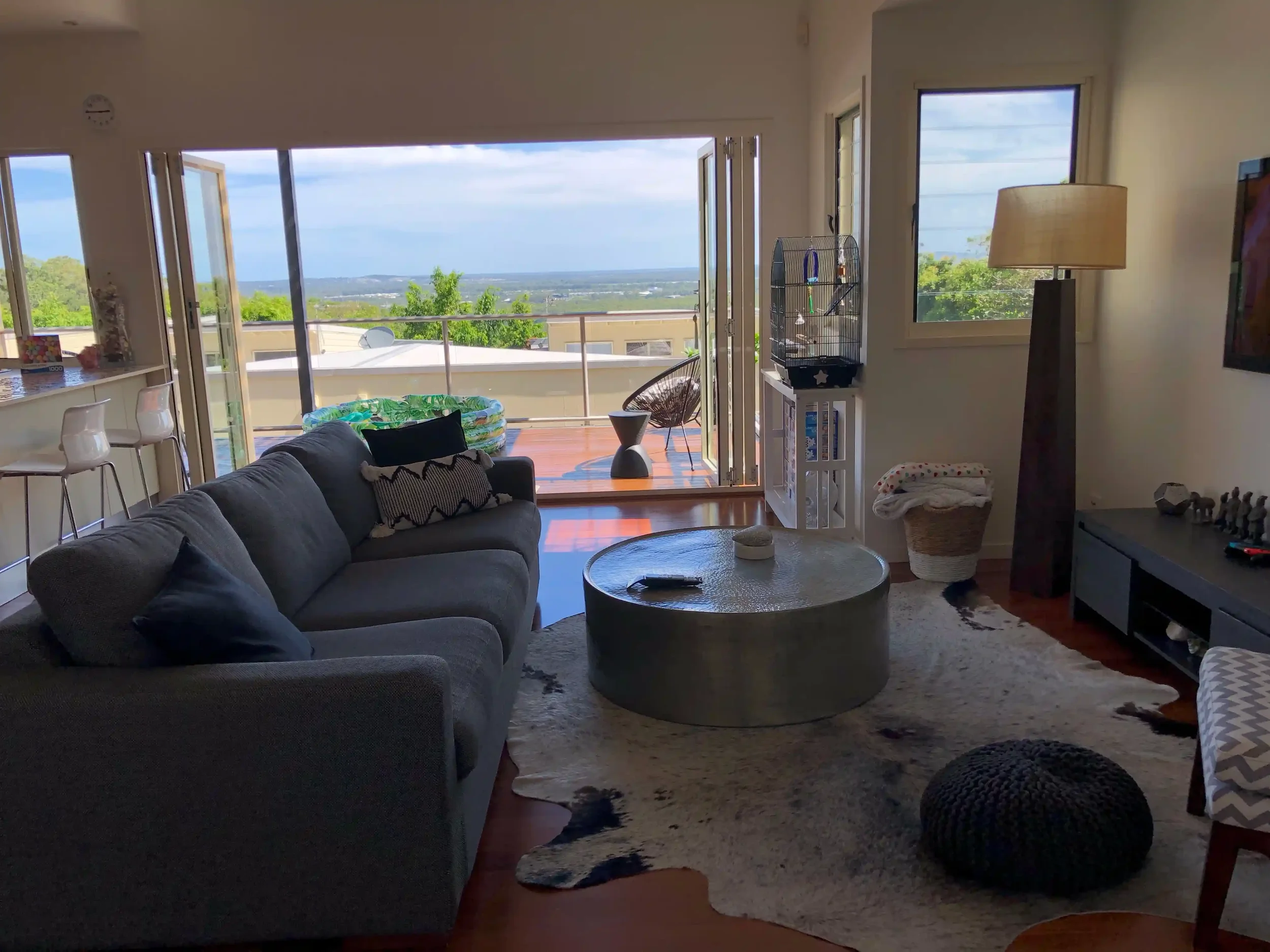Living room with large glass doors opening to a balcony overlooking a scenic landscape and blue sky