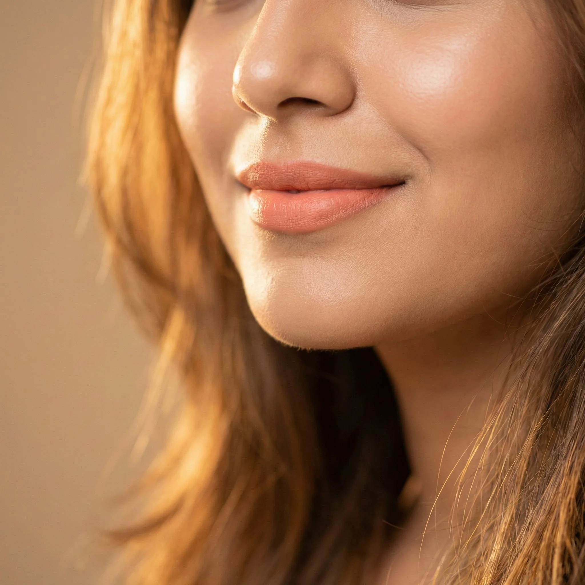Close-up of a woman's lips, nose, and part of her cheek with wavy auburn hair.