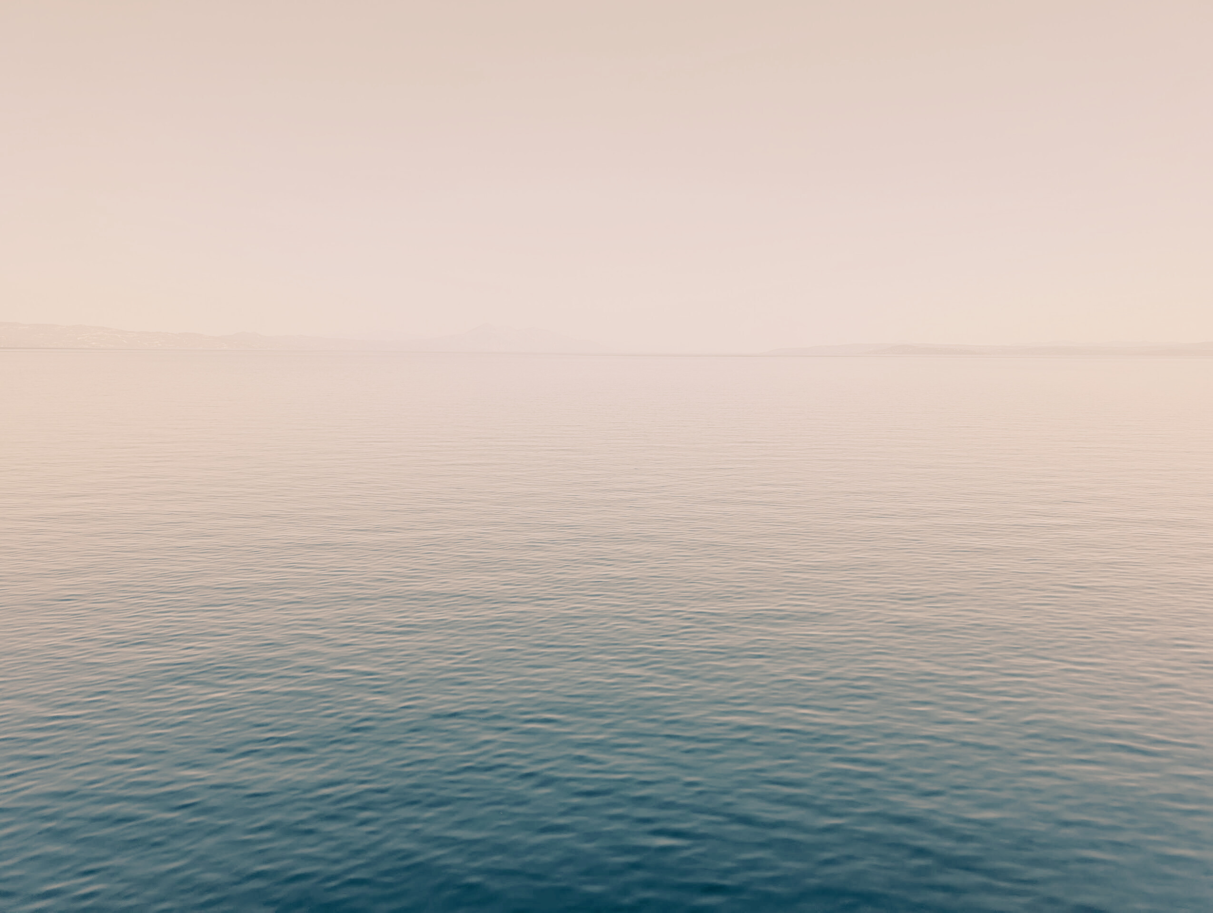 Calm ocean water with gentle ripples and a distant horizon under a clear sky.
