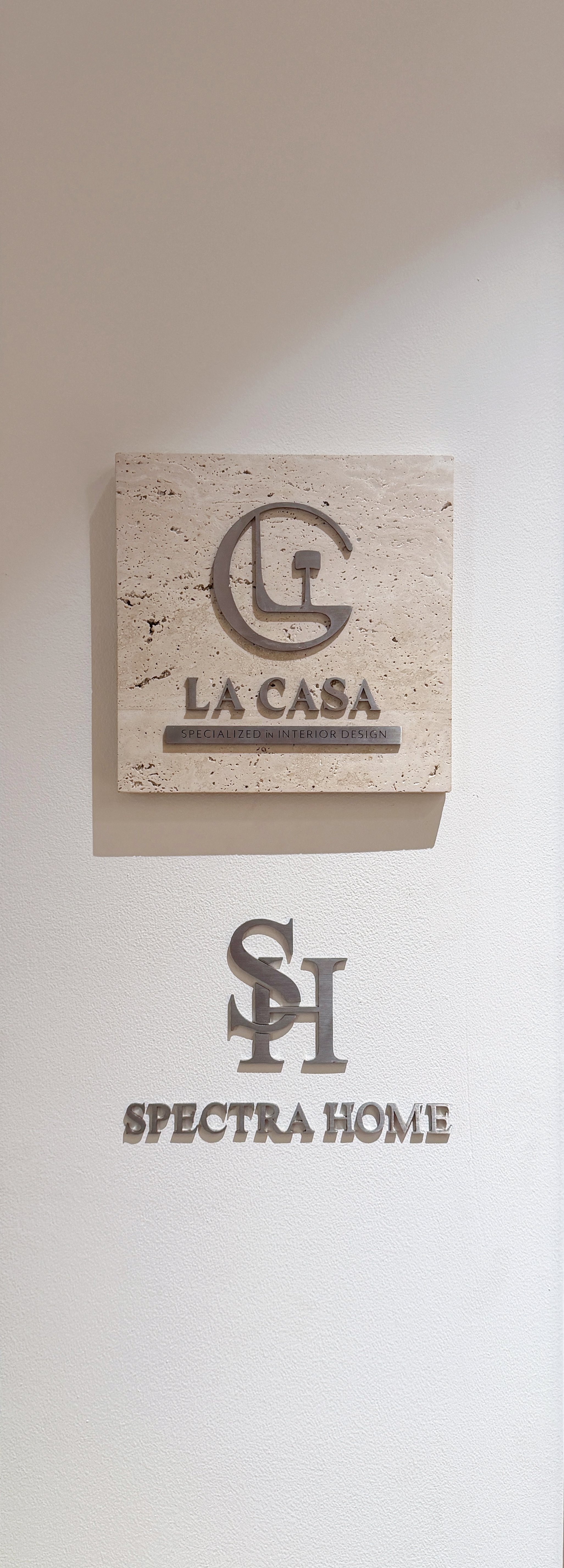 Photo of interior design company signs, including La Casa and Spectra Home, on a white wall.
