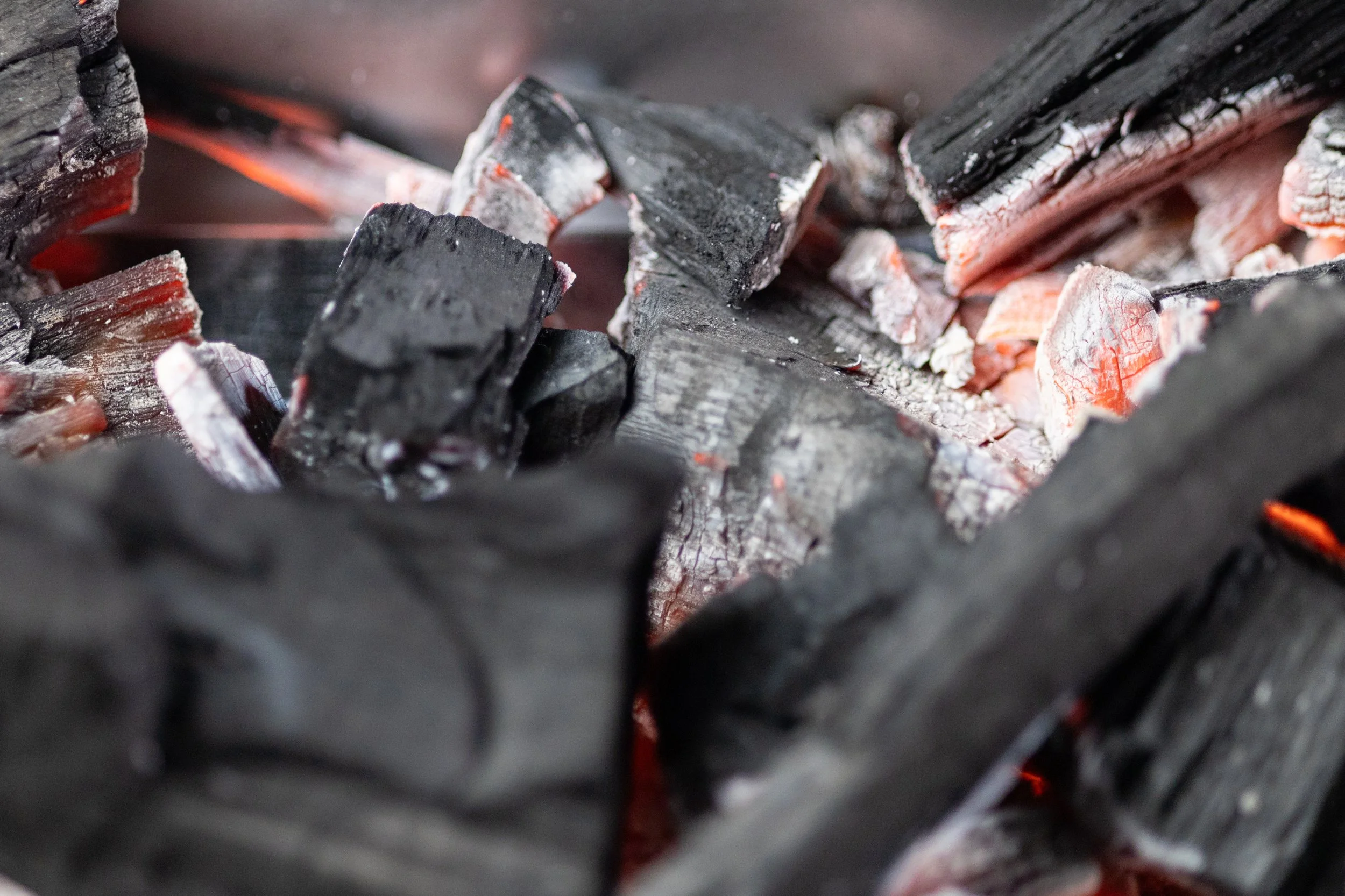 Close-up of burning hot charcoal with glowing red embers.
