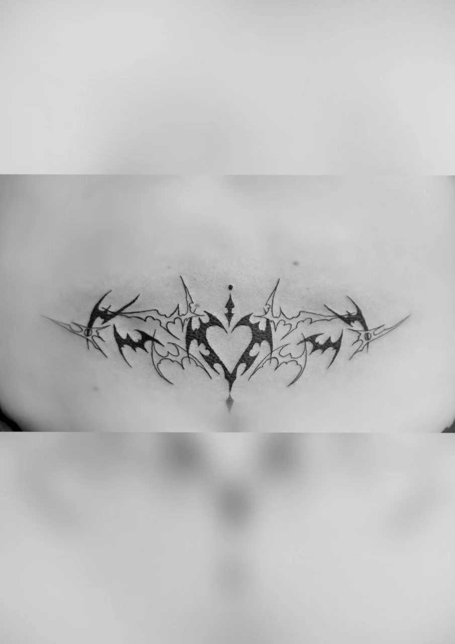 Tattoo eines symmetrischen, tribal-inspirierten Designs mit Herz in der Mitte