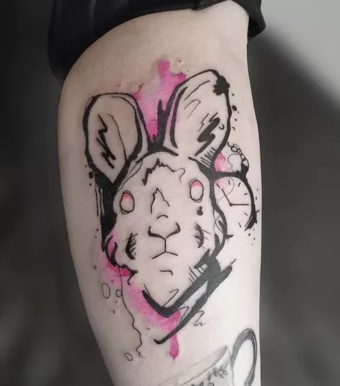 Tattoo eines Hasen mit Ohrmarken und rosa sowie schwarzen Akzenten am Oberschenkel.
