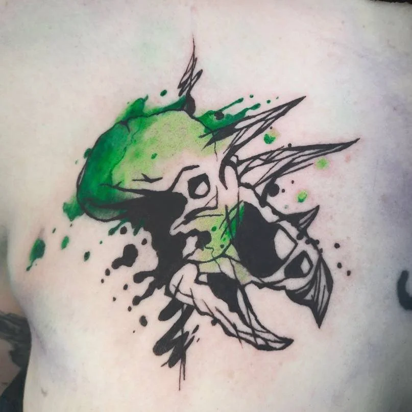 Tattoo eines Triceratops Schädels mit grünen und schwarzen Farben und abstrakten Elementen.
