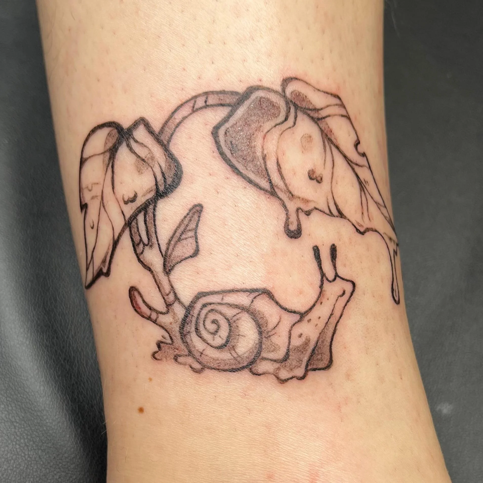 Tattoo einer Schnecke mit Blumen auf der Haut