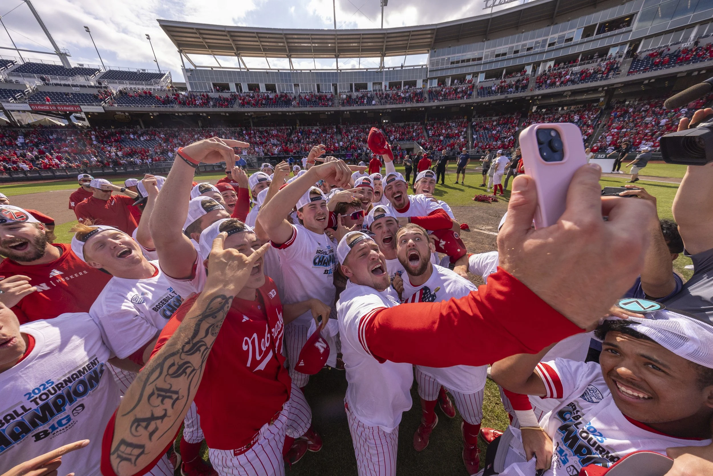 Baseball players celebrating on the field after winning a game, taking a selfie.