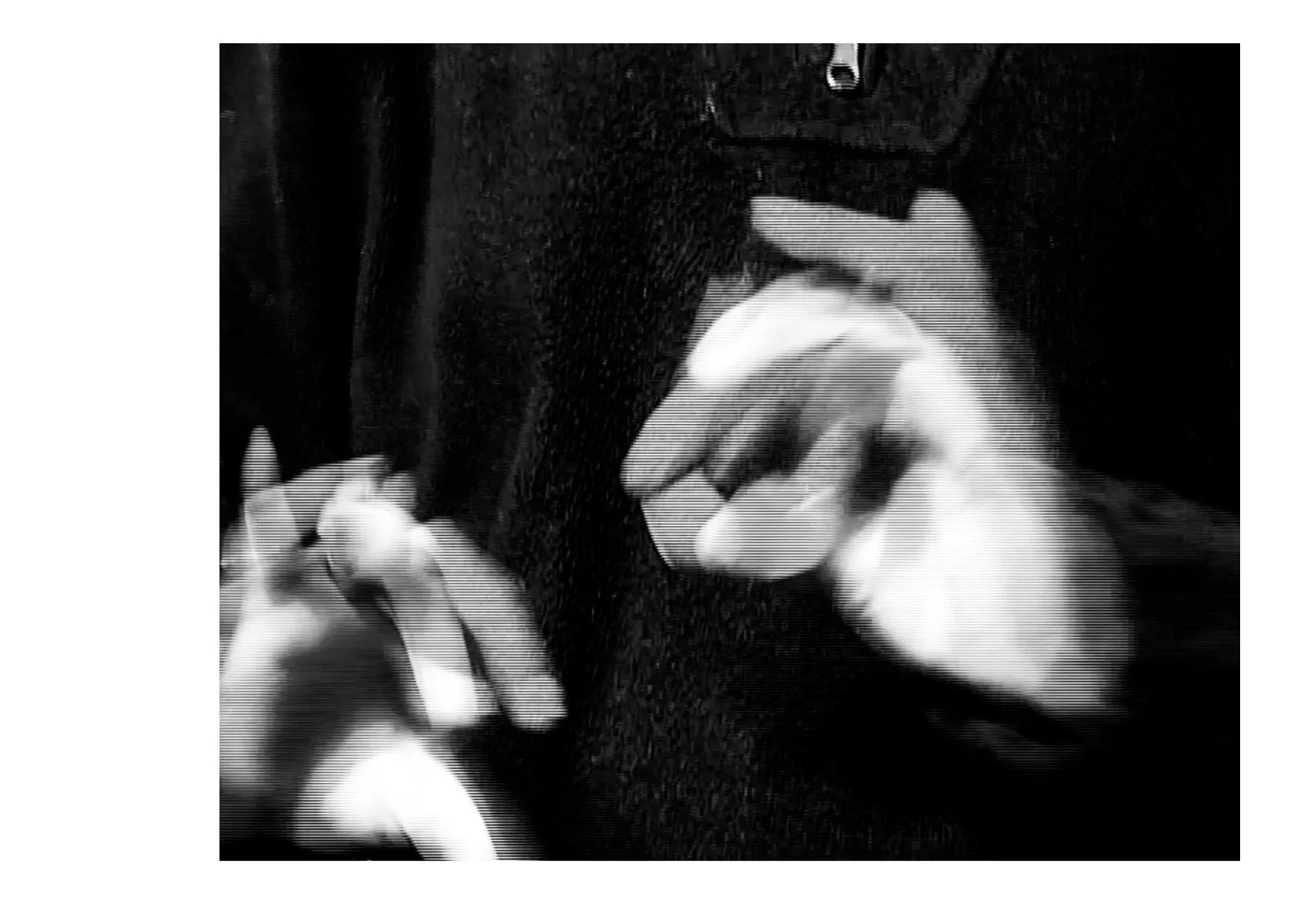 Mains d'une personne tenant une cigarette, habillée d'une veste noire, en noir et blanc.