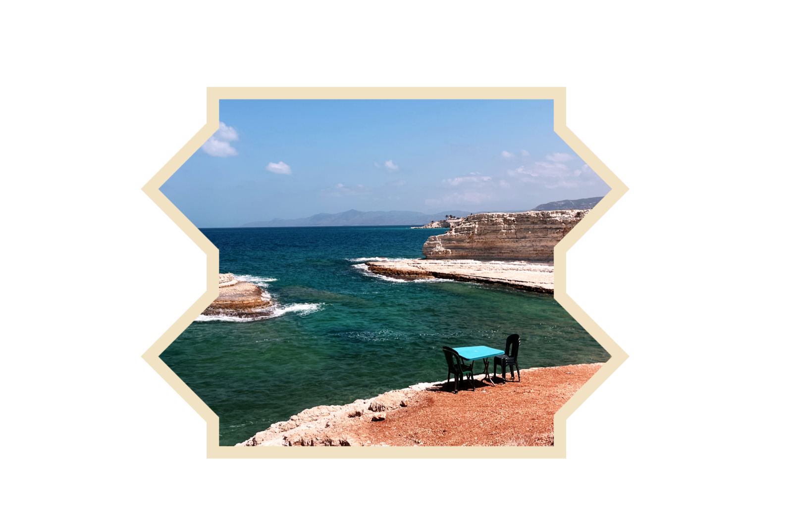 Seaside view with a small table and two chairs on rocky shore, cliffs, ocean, and a blue sky with clouds. Syria and travel