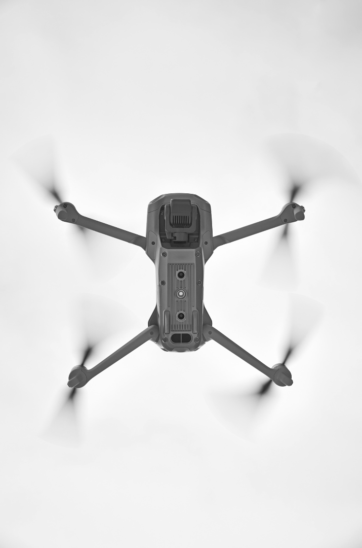 Top-down view of a quadcopter drone with four spinning propellers.