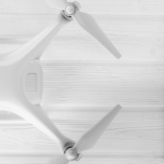 A white drone with two propellers resting on a white wooden surface.